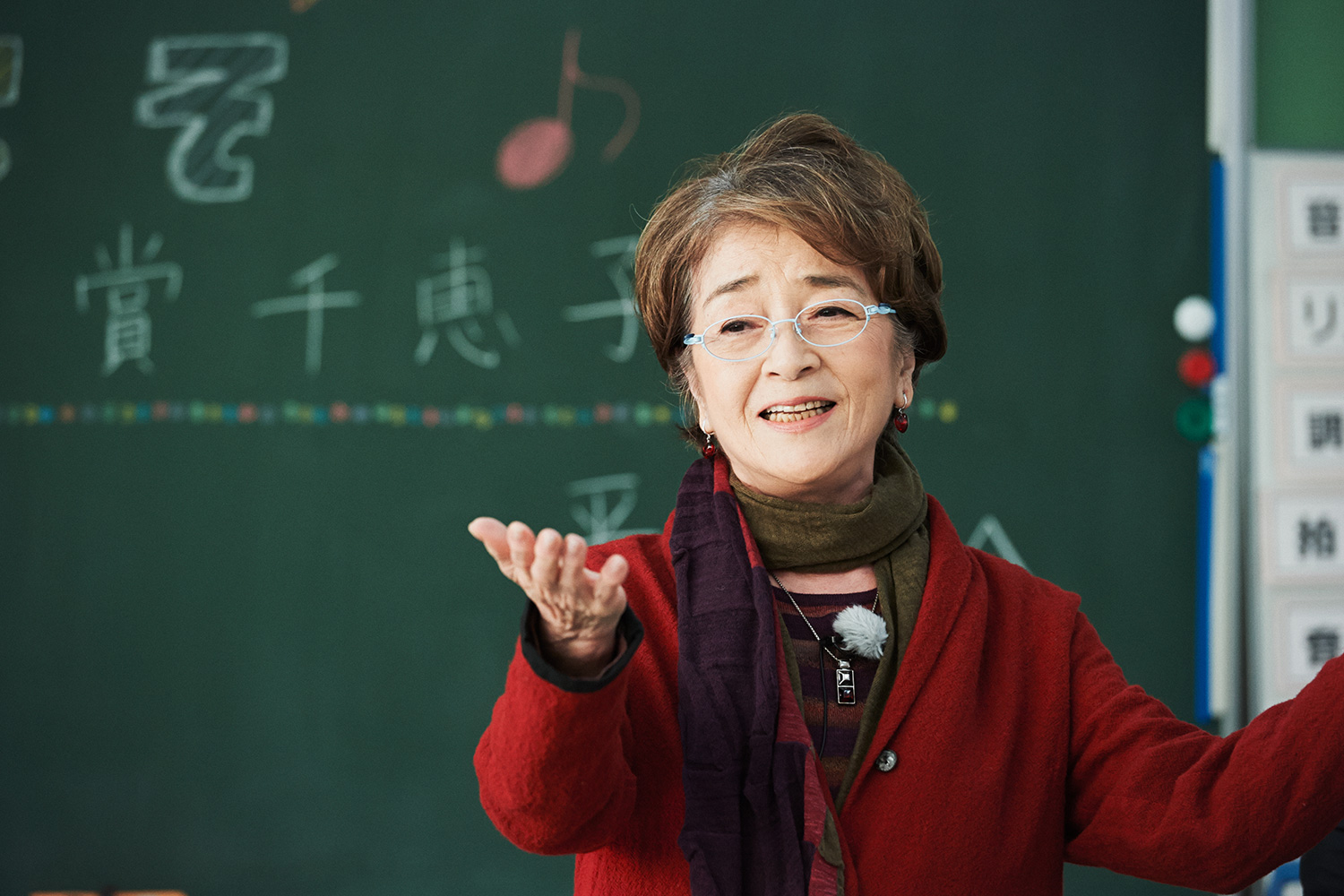 黒板に子供たちが書いた「ようこそ倍賞千恵子さん」のメッセージの前で歌う倍賞さん